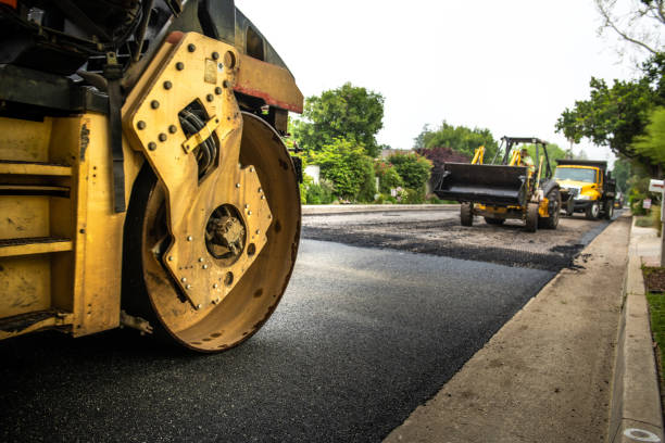 A shot of a road being resurfaced in a residential neighborhood in La Canada, California. Half of the street is paved and the other is unpaved. The machinery is lined up and working together.