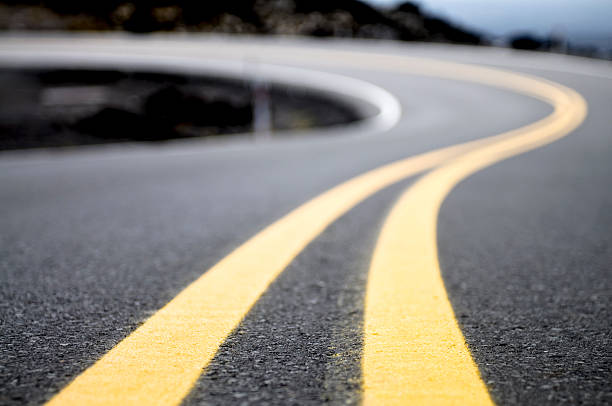 A double yellow line on a road curving into the distance.